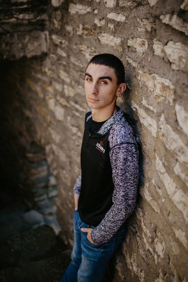 A person standing in front of a brick wall Description automatically generated